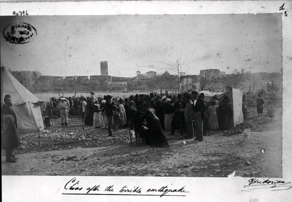 Το χειρουργείο για τους τραυματίες από τον μεγάλο σεισμό του 1881 και παροχή προμηθειών της Γαλλικής αποστολής βοήθειας. Στο βάθος τα τείχη του Κάστρου της Χίου με επάλξεις και ένας ψηλός πύργος. G. Krikorian (1881)”